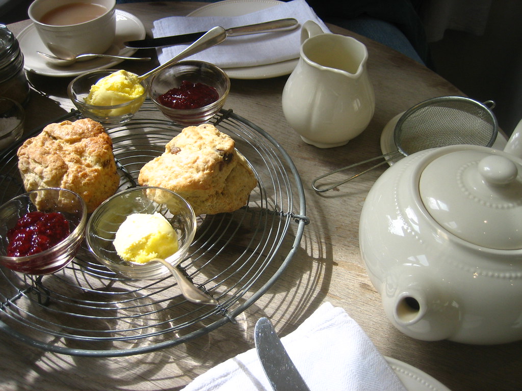 Scones with jam and clotted cream beside a teapot