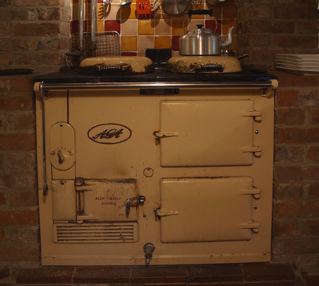 A cream-coloured Aga range cooker set into a brick fireplace