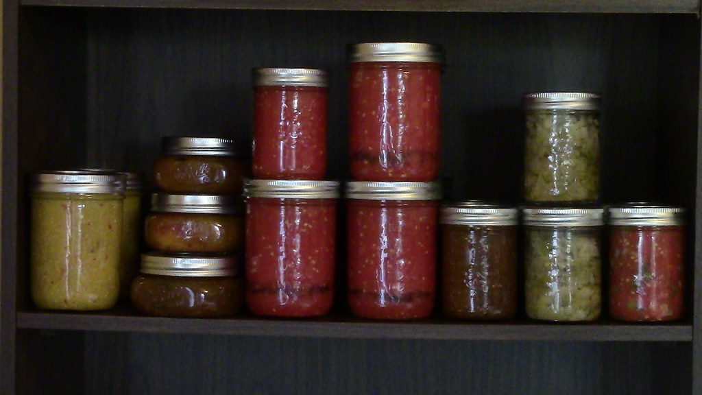 A shelf of homemade pickles and chutneys in glass jars